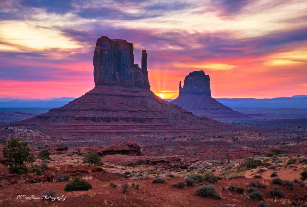 Monument Valley panoramic view of the Mittens and Merrick Butte under a bright blue sky, iconic red rock desert landscape on the Arizona–Utah border.