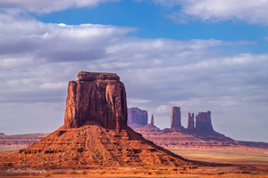 Monument Valley panoramic view of the Mittens and Merrick Butte under a bright blue sky, iconic red rock desert landscape on the Arizona–Utah border.