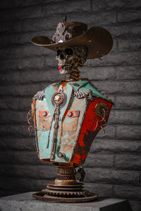 "Let’s Get Western" reclaimed metal sculpture by Paul Klaine, skeletal cowboy bust with wide-brimmed hat, bolo tie, turquoise and orange steel shirt, mounted on gear pedestal.