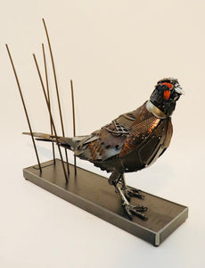 Losing Ground" – Metal pheasant sculpture by artist David Groenjes, crafted from reclaimed steel and found objects, displayed in an outdoor natural setting.