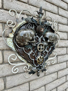 "Sprung on You" reclaimed metal wall sculpture by Paul Klaine, 25-inch heart-shaped artwork with opposing skulls, gears, and ornate steel scrollwork.