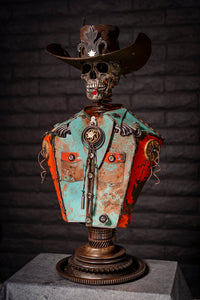 "Let’s Get Western" reclaimed metal sculpture by Paul Klaine, skeletal cowboy bust with wide-brimmed hat, bolo tie, turquoise and orange steel shirt, mounted on gear pedestal.